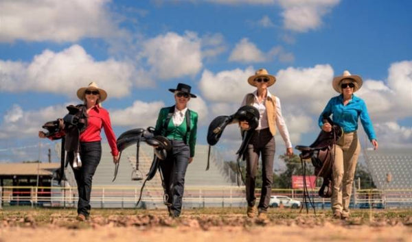 4 Horsewomen Striding Proudly Across an Arena