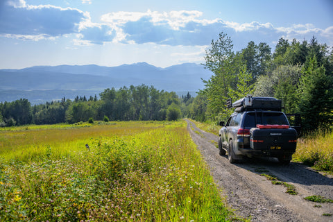 Overlanding rig driving down a dirt road on a sunny day