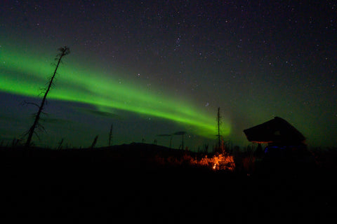 Night sky with the northern lights above overlanding rig at campsite