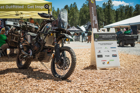 An fully-kitted ADV motorcycle parked at an outdoor exposition