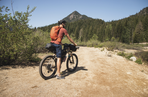 Man riding bike on road with backpack on