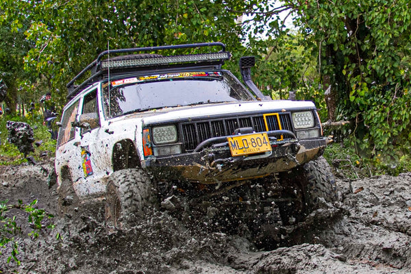 a jeep with a snorkel off-road driving through mud