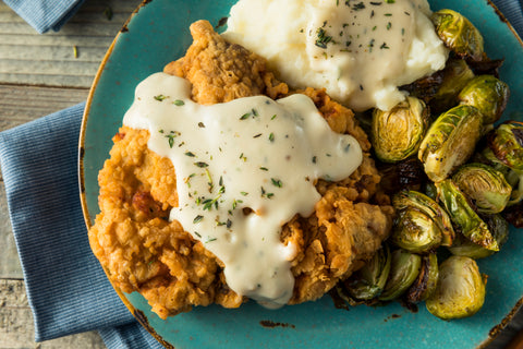 Country fried steak in creamy gravy with potatoes smothered in thick gravy