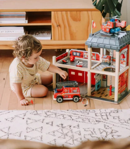 child playing with wooden fire station