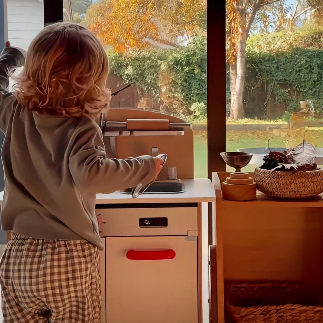 Child playing with pretend wooden kitchen