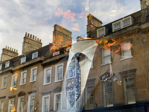 Caridi in shop window with view of Milsom Street reflecting on it. 