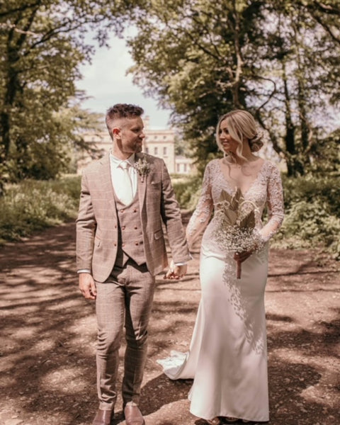 Ted brown wedding suit for groom worn on outside walk next to bride.