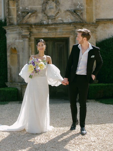 Modern groom wearing a black suit next to bride.