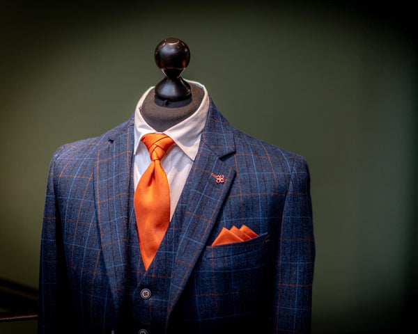 Navy suit for men shown on a mannequin with a white SUAVE OWL shirt and vivid orange accessories.