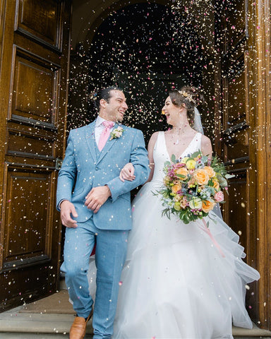 Pale blue suit for groom's is worn whilst couple is showered with confetti.