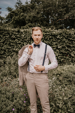 Elwood suit, cream suit, with model hanging jacket over shoulder.