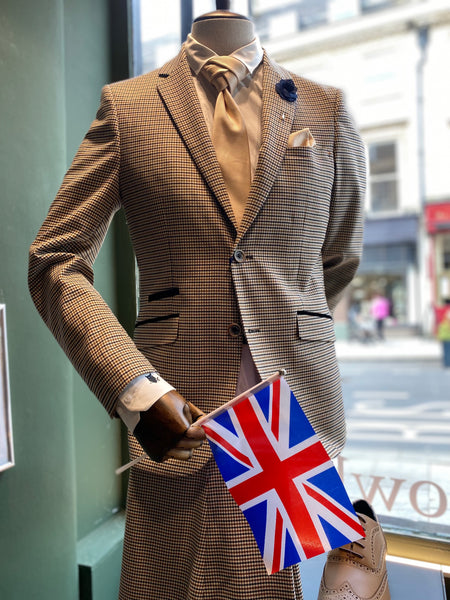 A mannequin wears the Elwood suit with champagne accessories. It is holding the Union Flag.