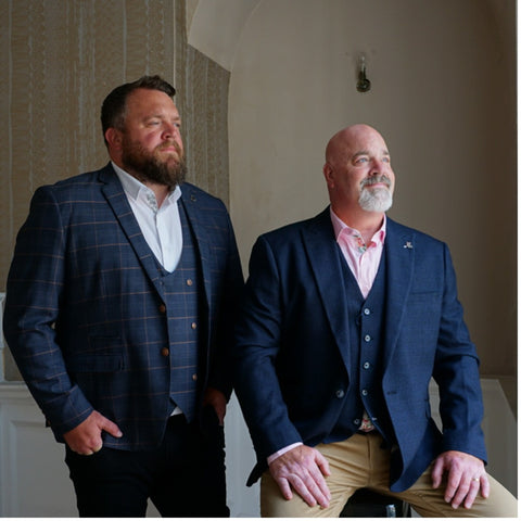 Co-founder Tony and his father wearing men's smart casual outfits with suit jackets.