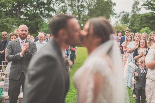 Couple have their first kiss. Couple is out of focus, allowing the guest's faces to be visible.