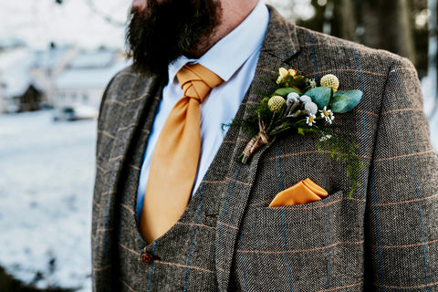 Winter groom wearing a brown suit for men with yellow accessories.