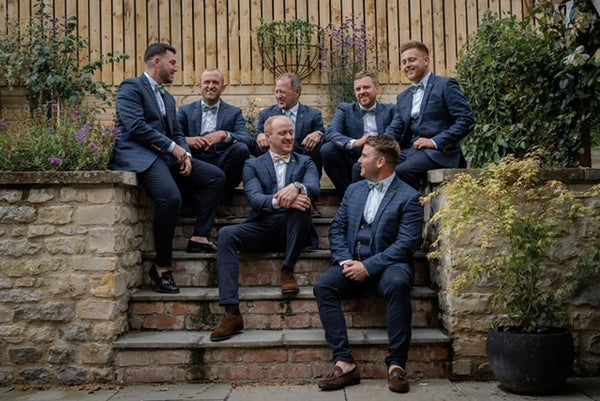 Groom's party sat on stairs outside venue.