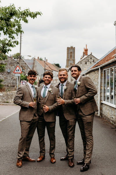 Real groom's party wearing a brown suit for men with green accessories.