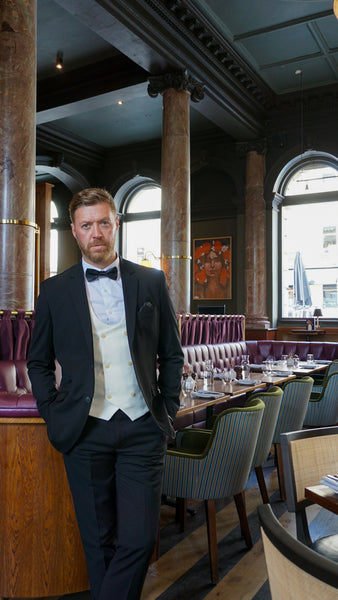 Black tie outfit for men consisting of black Marco suit with a SUAVE OWL white shirt and black bow tie.