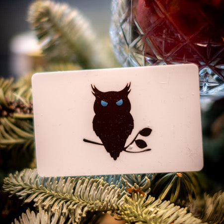 SUAVE OWL voucher sits on branches of Christmas tree.