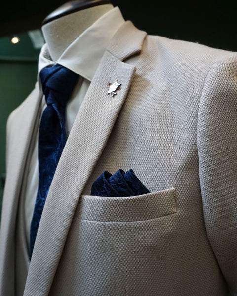 Men's suit in stone with navy accessories on mannequin