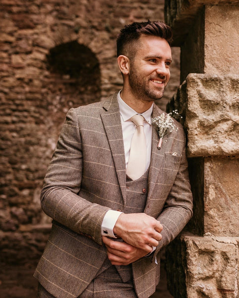 Groom wearing the full Ted suit stands under shade.