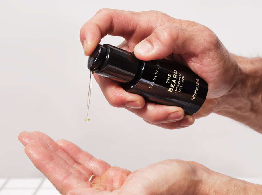 The Beard conditioning oil by Caldera Lab being dispensed into the palm of a hand.