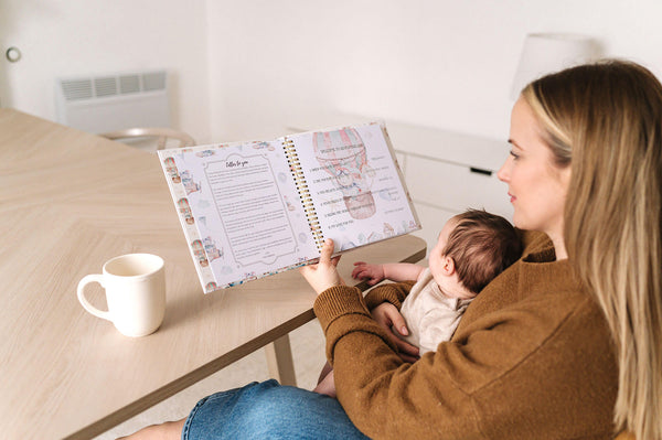mother looking at a baby book while holding her baby