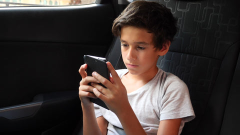 teen boy playing mobile game backseat of car