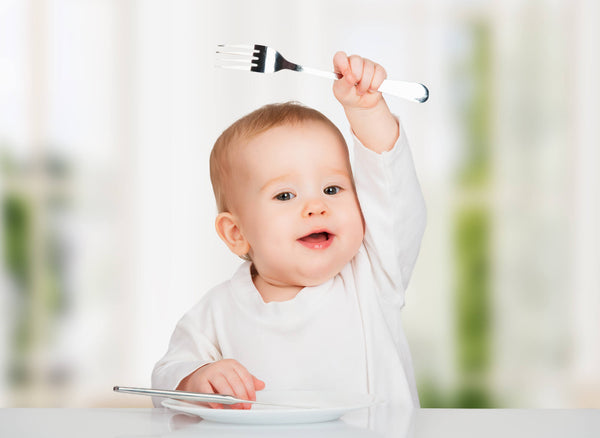 happy baby with a knife and fork eating food