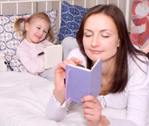 mother and daughter laying in bed  reading book