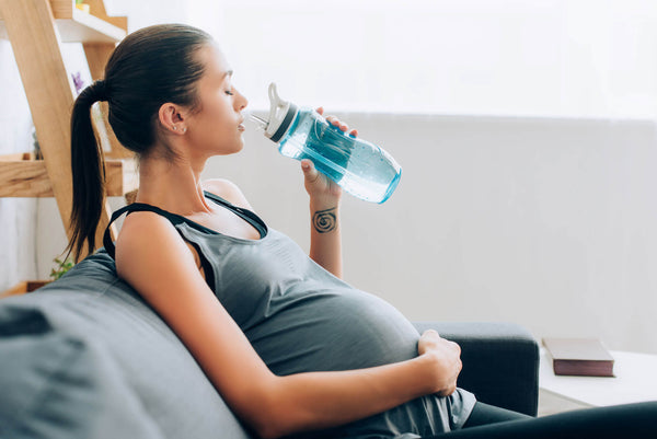 pregnant woman drinking from a water bottle