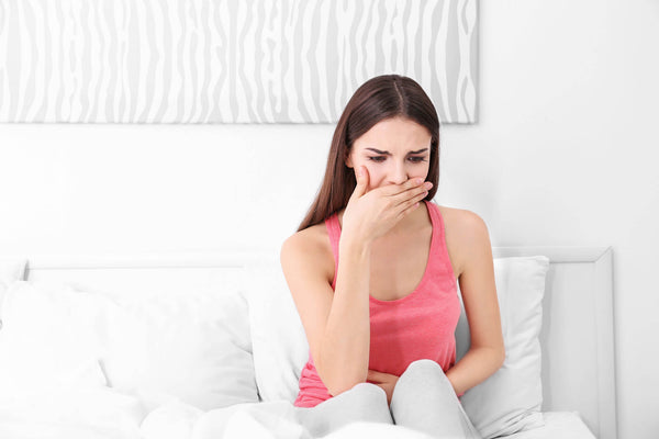 sick young woman sitting on bed at home