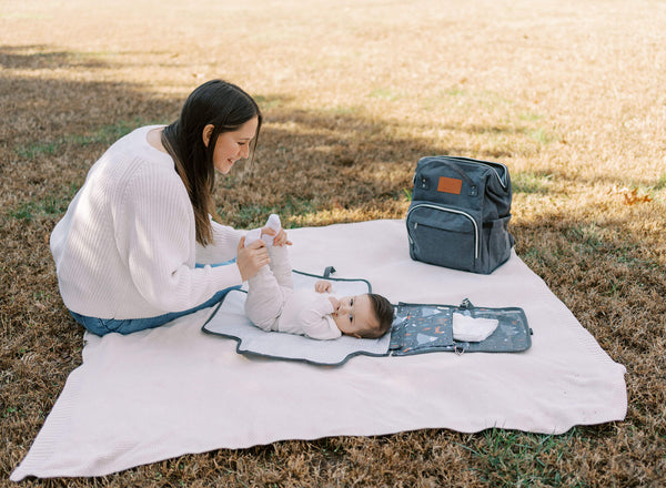 changing baby diaper in a park