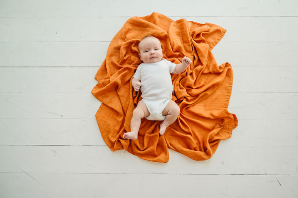 baby lying on a muslin swaddle blanket