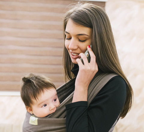 Woman on the phone while wearing her baby
