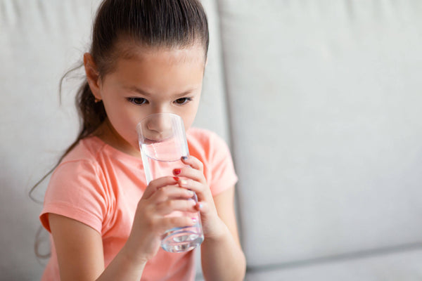 Girl Drinking Water Sitting On Sofa At Home