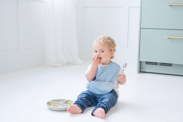 cute baby sitting on the floor having baby meal