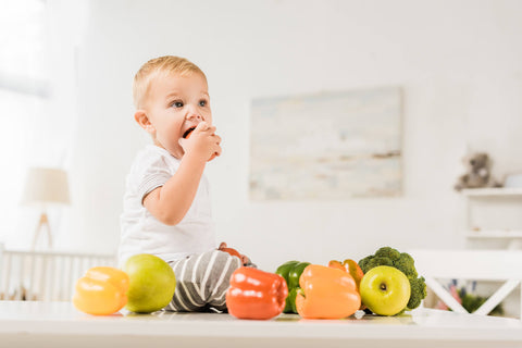 Cute Toddler Eating Sitting Table Surrounded Fruit Vegetables