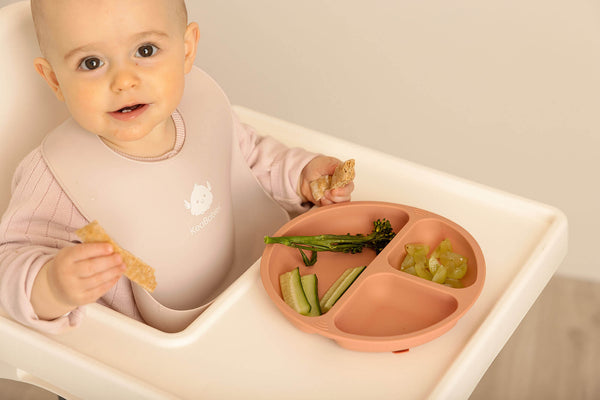 baby eating meal on a high chair