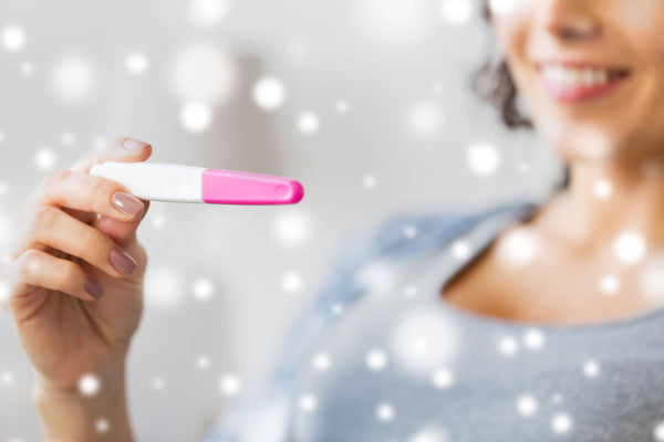 Close up of happy woman with home pregnancy test