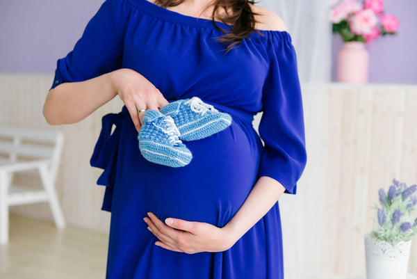 pregnant woman photoshoot with blue baby shoes