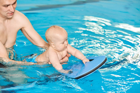 father teaching a baby to swim