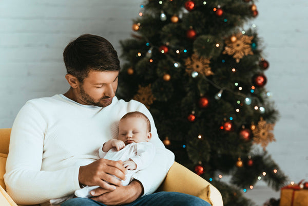 Happy Father Holding Sleeping Baby While Sitting Christmas Tree