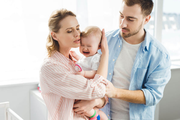 parents comforting a crying baby in pain