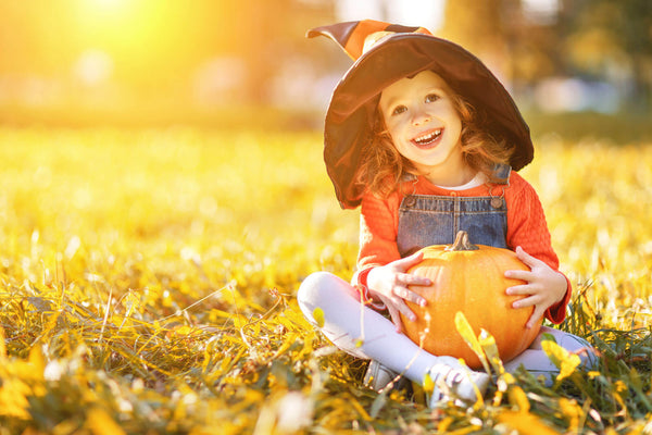 Child girl with pumpkin outdoors on Halloween