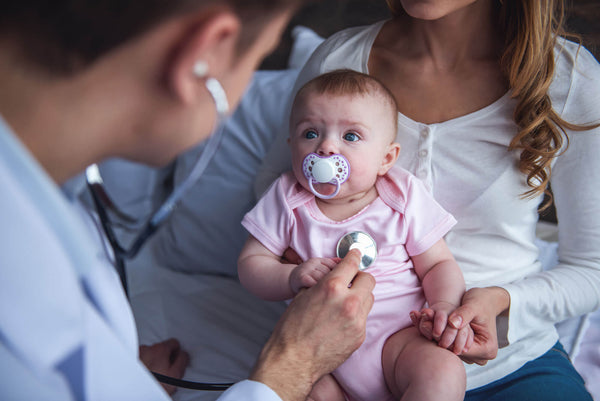 Young Mom Holding Her Cute Baby While Doctor Listening