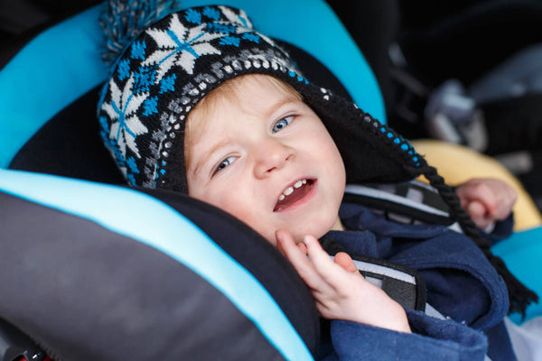 Adorable toddler boy sitting in safety car seat