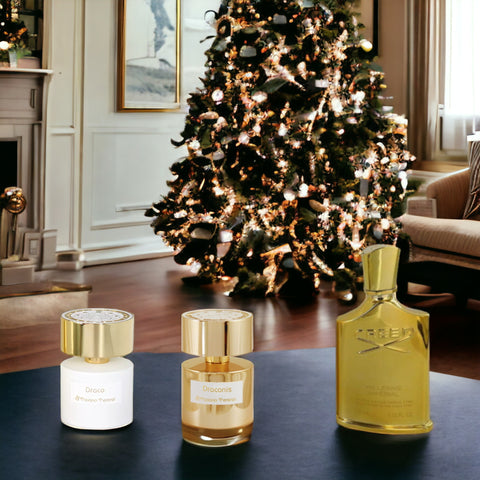 Three bottles sitting on a table in front of a lit christmas tree in an upscale room