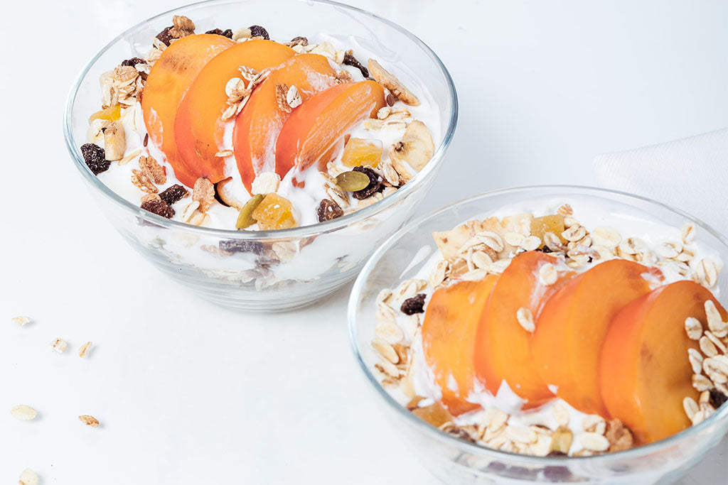 Two bowls full of Greek yogurt and fresh fruit to reduce bloating.