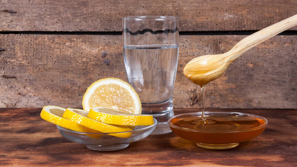 A glass of water, honey, and slices of lemons. Concept of using honey lemon water to aid weight loss.